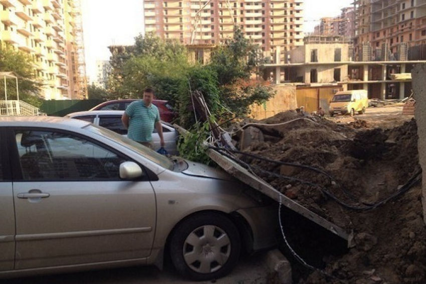 В Краснодаре экскаватор опрокинул бетонный забор на припаркованные легковушки